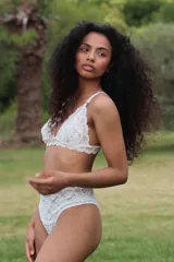 Bralette de encaje blanco con diseño floral, tirantes regulables y terminaciones festoneadas.