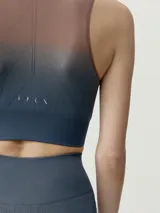 Top deportivo sin mangas de diseño degradado que transiciona de beige en los hombros y pecho a verde oscuro en la parte inferior, con escote redondo y sostén integrado.
