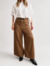 Pantalón de tiro alto y calce fluido, color marrón, confeccionado en mezcla de tencel y lino. Presenta una silueta amplia de pierna ancha con bolsillos frontales aplicados con solapa y trabillas para cinturón.