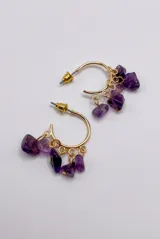 Aros de tipo argolla dorada con dijes colgantes de piedras de amatista en tonos lilas y violetas.