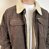 Chaqueta de pana color beige con forro de corderito en el cuello y el interior. Tiene cierre con botones, bolsillos en el pecho y bolsillos laterales.