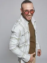 Camisa de manga larga confeccionada en algodón, con diseño de cuadros en tonos blanco y verde oliva. Presenta cuello clásico con botones y cierre frontal abotonado.
