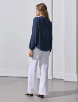 Blusa azul marino de Zac & Rachel con cuello a la base, abertura central con botones y detalle de broderie en el frente. Tiene mangas largas con terminación elastizada.