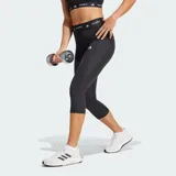 Calza capri deportiva Adidas Techfit de color negro, con diseño de compresión y tiro alto. Presenta una cintura elástica ancha con la inscripción "TECHFIT" repetida y el logo de la marca en blanco en la pierna izquierda.