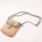 Cartera bandolera de rafia color beige con detalles en verde menta. Tiene una solapa con cierre de broche y correa ajustable.
