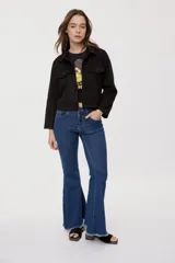 Campera negra de efecto gamuzado con cuello camisero, cierre frontal de botones, bolsillos plaqué en el pecho y detalles de costuras decorativas y calados.