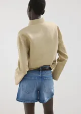Short de denim azul de tiro medio, con diseño recto y clásico de cinco bolsillos, presillas para cinturón y cierre frontal con botón y cremallera.