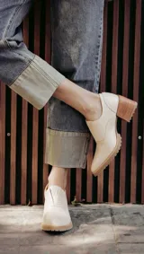 Zapato de cuero color beige, con taco de madera y suela dentada. Presenta un diseño slip-on con detalles de textura en relieve en los laterales y el empeine.