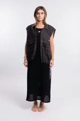 Chaleco de denim negro con efecto deslavado, diseño sin mangas, bolsillos frontales con solapa, costuras en contraste y botones metálicos.