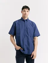 Camisa de manga corta azul con estampado de lunares blancos, cuello abotonado y bolsillo en el pecho.