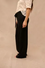 Pantalón largo negro de corte holgado, con cintura elástica ajustable mediante cordón con lazo.