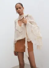 Short tipo falda pantalón de tiro bajo, color tostado, con diseño de tablas y bolsillos laterales.
