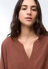 Blusa de viscosa color marrón con escote en V, mangas tres cuartos con puños elásticos y corte holgado.