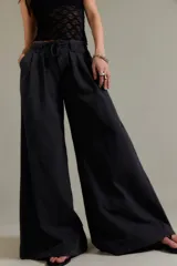 Pantalón chino de tiro bajo, color negro, pierna muy ancha, con cintura elástica con cordón ajustable y pinzas en la parte superior.