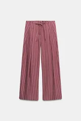 Pantalón de tiro medio color bordó con diseño de rayas verticales finas en tono claro. Presenta corte holgado, bolsillos laterales y cintura ajustable con cordón para atar.