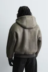 Cazadora relaxed fit de Zara confeccionada en tejido efecto piel con acabado lavado, interior de borreguillo a contraste, capucha, bolsillos de vivo en la cadera, acabados en rib y cierre frontal de cremallera.