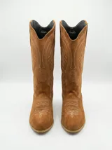 Bota estilo texana de caña media, confeccionada en gamuza color camel, con bordados decorativos en hilo claro y taco cuadrado bajo.
