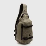 Mochila tipo bandolera de un solo hombro, color tostado, con correas ajustables negras y cierre frontal.