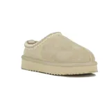 Pantufla tipo mule de cuero gamuzado color beige, con detalle de costura decorativa en el borde superior y suela de plataforma plana con base dentada.