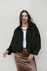 Campera bomber de tela gamuzada negra, con diseño oversize, mangas amplias tipo murciélago y cierre frontal metálico.