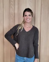 Sweater de punto color beige, con cuello en V, manga larga con puños acanalados y diseño holgado.