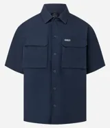 Camisa de manga corta color azul marino de corte boxy, con cuello inglés, cierre frontal de botones metálicos a presión y bolsillos cargo en el pecho.