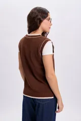 Chaleco de punto estilo varsity color marrón, con cuello redondo y detalles de rib en color beige claro en los bordes y sisas.