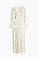 Vestido maxi de viscosa color marfil con estampado floral azul, escote en V pronunciado con ribete de encaje, mangas largas abullonadas y corte entallado.