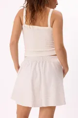 Conjunto deportivo compuesto por un buzo con cierre frontal y una falda corta, confeccionados en algodón liviano. El buzo presenta cuello alto, mangas largas con puños elásticos y un diseño holgado.