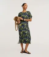 Vestido midi de corte recto y cuello redondo, confeccionado en viscolycra con estampa de follaje en tonos verdes y azules. Presenta mangas cortas con recortes y aberturas laterales en el ruedo.