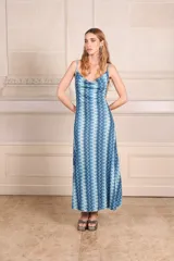 Vestido midi con estampado de ondas verticales en tonos fucsia, verde y plateado. Tiene breteles finos, escote drapeado y espalda baja.