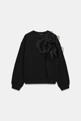 Sudadera de algodón con cuello redondo y manga larga, caracterizada por un detalle de flor con volumen confeccionada en organza sobre el hombro. Presenta terminaciones en rib en puños y ruedo.