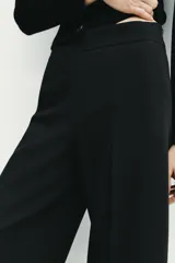 Pantalón culotte negro de tiro alto con bolsillos delanteros, pernera ancha y corta, y raya marcada al frente. Cuenta con cierre lateral con cremallera oculta.