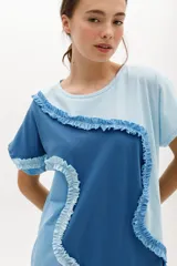 Vestido corto de algodón, con bloques de color en tonos pastel (amarillo claro, beige y rosado pálido) unidos por volados fruncidos en tonos marrón claro y amarillo. Presenta cuello redondo y mangas cortas.