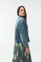 Campera de denim azul con bolsillos frontales con solapa, cuello clásico y cierre de botones metálicos.