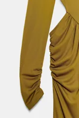 Vestido largo color mostaza con cuello alto, manga larga drapeada y detalles cut out laterales. Presenta frunces en la cintura y la espalda, y bajo recto.