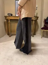 Jean de corte flared confeccionado en denim negro lavado, con aplicación lateral de encaje con flecos y lentejuelas.