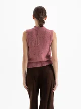 Chaleco de punto con escote en V y cierre frontal de botones. Presenta un diseño en color rosa con sutiles destellos metalizados y terminaciones en ribb elástico en sisa y cintura.