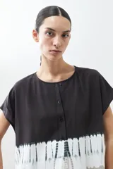 Blusa gris con estampado tie dye, de manga corta y cuello redondo con botones.