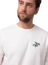 Remera de manga corta y cuello redondo, color vainilla, con estampado gráfico pequeño en el pecho y logo de la marca en el dobladillo.