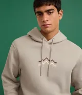 Hoodie cerrado de algodón con felpa, color beige claro, corte comfort. Presenta capucha con cordón ajustable, bolsillo canguro y puños y ruedo ajustados. Estampa minimalista de montañas en el pecho con líneas en tonos marrón, negro y rosado.