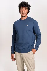 Buzo de cuello redondo en color azul, con diseño liso y logo bordado pequeño en el pecho. Presenta puños y ruedo acanalados.