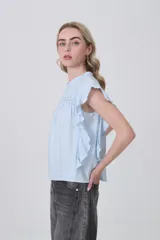 Blusa celeste de viscosa con diseño holgado, cuello a la base con detalle de volados, mangas cortas con volados y detalle de punto smock en el pecho.