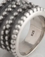 Anillo ancho de plata 925 con diseño de bandas texturizadas en bajo relieve y acabado empavonado.