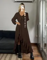 Vestido largo color marrón, con escote en V, mangas largas con puños y detalle de encaje en el pecho. Presenta un diseño asimétrico con volados en el ruedo y una abertura frontal.