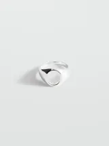 Anillo de acero inoxidable plateado con diseño de sello y placa ovalada central.