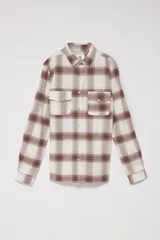 Camisa de manga larga a cuadros color beige y marrón, con cuello clásico, cierre frontal con botones a presión, dos bolsillos con solapa abotonada en el pecho y puños abotonados.