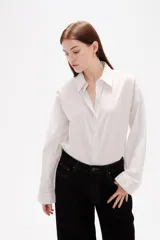 Camisa de algodón con diseño de rayas verticales finas, cuello clásico, cierre frontal con botones y mangas largas con puños abotonados.