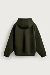 Canguro relaxed fit de tejido técnico con elasticidad efecto neopreno, color verde militar, con capucha ajustable, cierre frontal de cremallera de doble dirección, bolsillos frontales tipo canguro y acabados en rib.