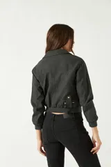 Campera corta negra con corte entallado, cierre frontal asimétrico y bolsillos con cremallera.